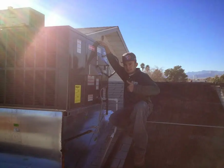 HVAC technician performing Air Duct Cleaning on a rooftop unit in Colton